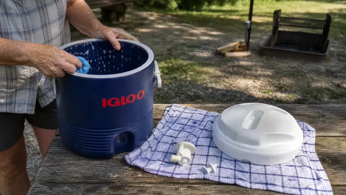 The insulated water dispenser sitting disassembled with its spout and lid removed, drying on a towel after cleaning